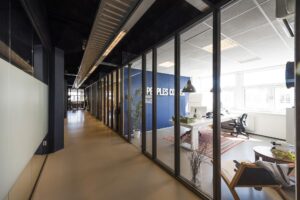 Moderne kantoorruimte aan de Anthony Fokkerweg met glazen wanden en zicht op een ingerichte werkplek.